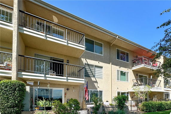 Front view of a three-story residential building with multiple balconies.