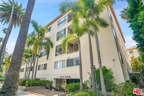 Front view of a multi-story apartment building with large windows.