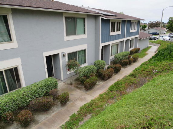 Front view of a two-story residential building with a walkway and shrubbery.