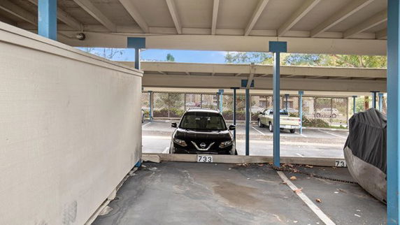 Covered parking area with cars parked, featuring designated parking spots.