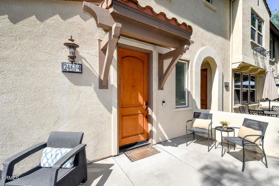 Front view of a two-story house with a wooden door and small patio area.