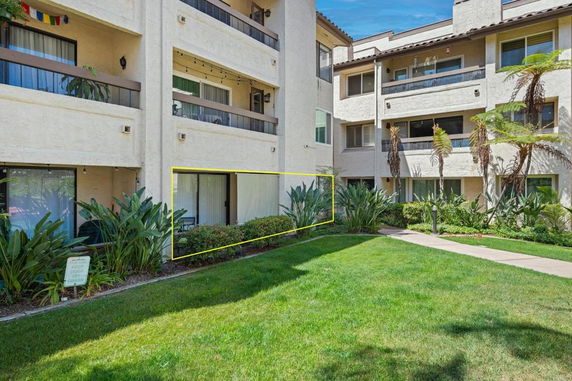 Front view of a multi-story building with balconies and surrounding greenery.