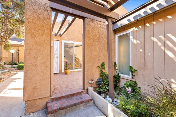 Exterior view of a house entrance with a small brick porch and plants.