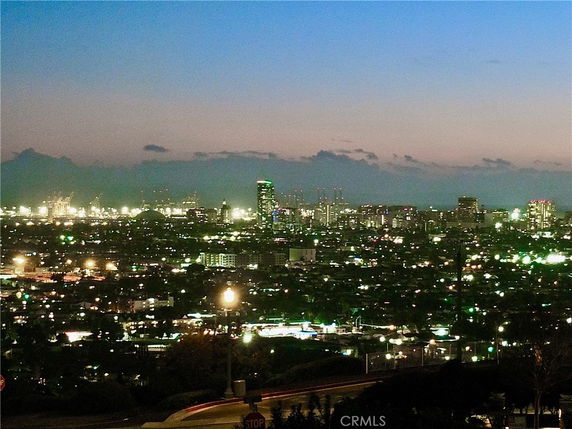 Panoramic view of a city skyline at dusk with illuminated buildings.