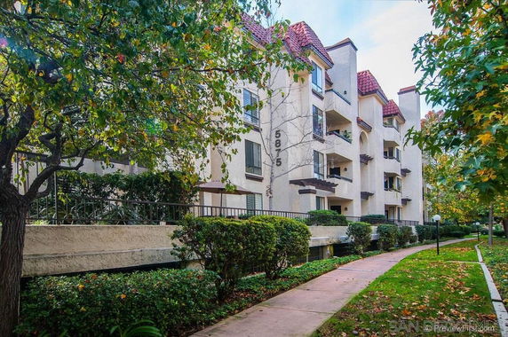 Front view of a multi-story residential building with balconies and red tile roofing.