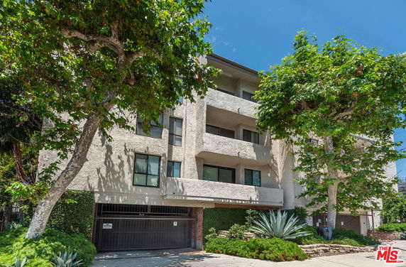Front view of a multi-story residential building with balconies and a garage entrance.