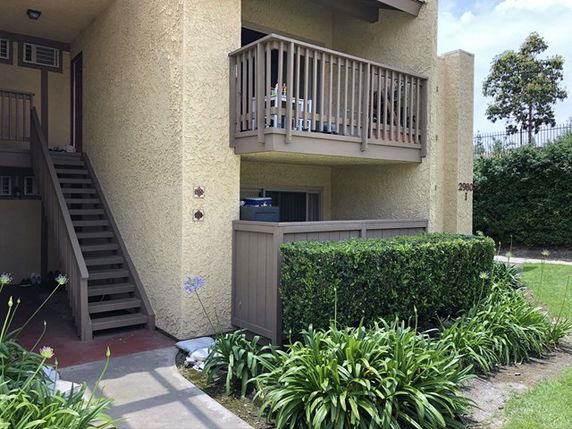 Front view of a multi-story building with a staircase and balcony.
