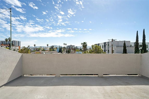 Panoramic view from a building overlooking a cityscape with distant buildings and trees.