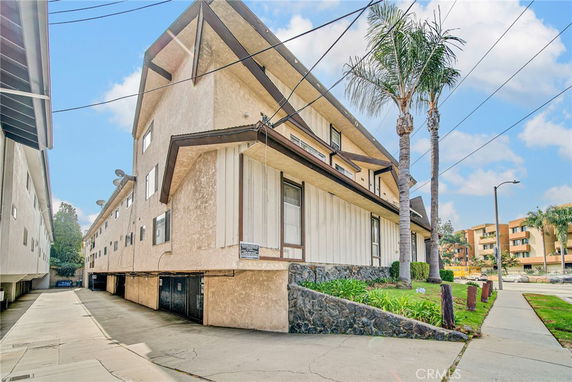 Front view of a multi-story residential building with wooden accents and a sloped roof.