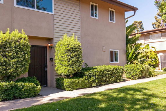 Front view of a two-story house with bushes and a pathway leading to the entrance.