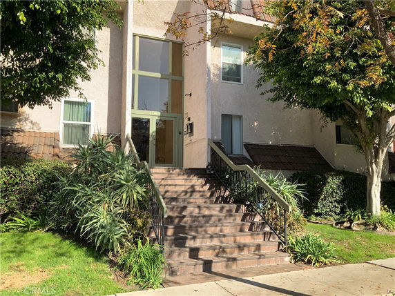 Front view of a two-story house with a staircase entrance and large windows.