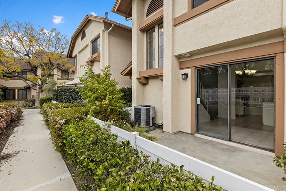 Front view of a multi-story building with a sliding glass door and landscaped pathway.