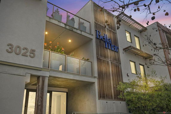 Front view of a modern multi-story building with a balcony and visible entrance.