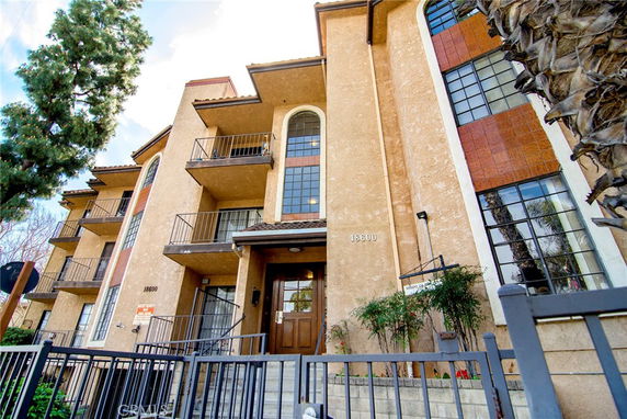 Front view of a multi-story residential building with balconies and large windows.