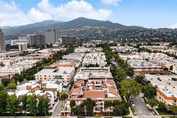 Aerial panoramic view of an urban area with multiple buildings and mountainous background.