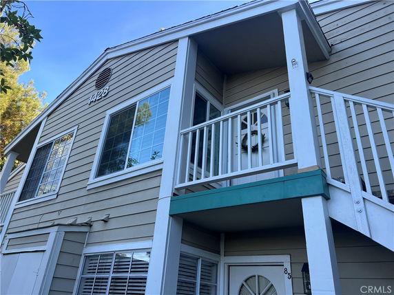 Front view of a two-story house with a small balcony and multiple windows.