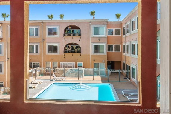 View of an apartment complex with a central swimming pool and lounge chairs.