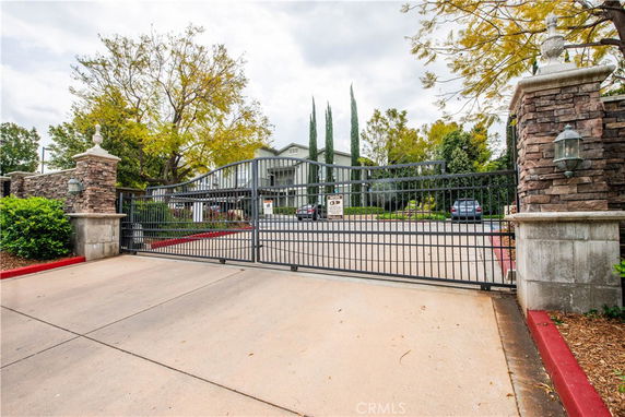 Front view of a gated residential building with a metal fence and stone pillars.