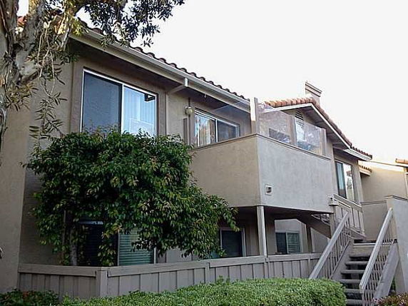 Front view of a two-story residential building with a balcony and external staircase.