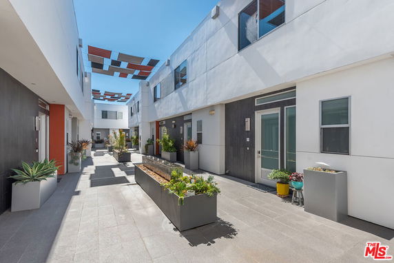 Front view of a modern multi-story apartment complex with decorative outdoor planters.