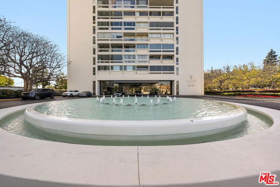 Front view of a high-rise building with a water fountain in front.