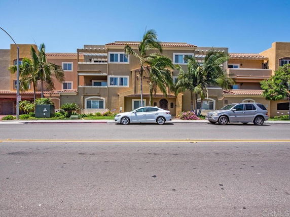 Front view of a multi-story building with multiple balconies and palm trees.