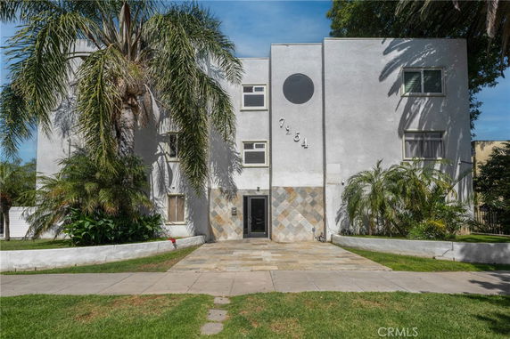 Front view of a three-story building with a symmetrical facade and round window feature.