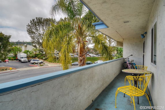 View from a balcony overlooking parked cars and greenery.