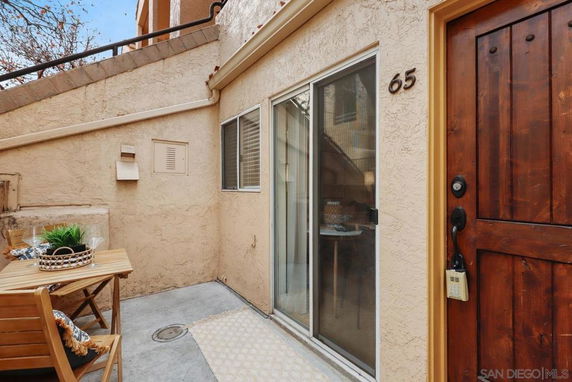 Front view of an outdoor area with a small patio adjacent to a house entrance.