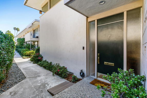 Front view of a modern residential building entrance with a number 3 door and surrounding walkway.