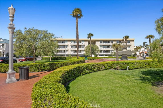 Front view of a multi-story building with balconies and landscaped surroundings.