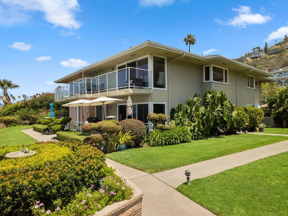 Front view of a two-story house with a balcony and well-maintained garden.