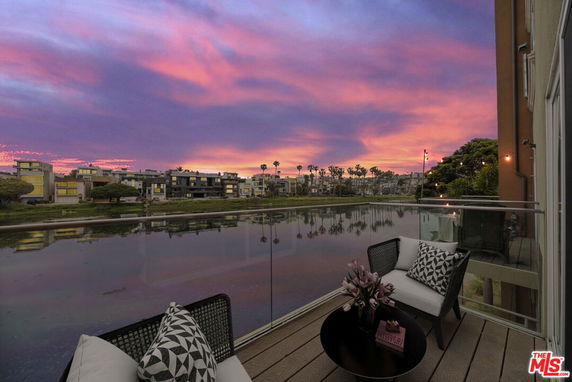 Balcony view of surrounding area with waterway and buildings at sunset.