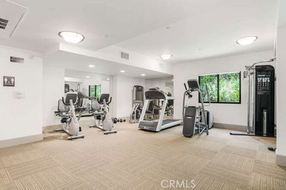 Indoor gym area with exercise equipment and mirrors on the wall.