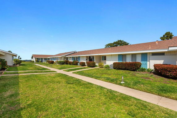 Front view of a row of single-story houses with blue doors and brown roofs.