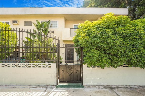 Front view of a two-story building with a gated entrance and lush greenery.