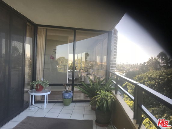 Balcony view from a building with glass railing and potted plants.