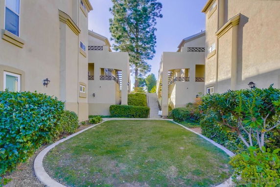 View between two buildings showcasing outdoor stairway and surrounding greenery.