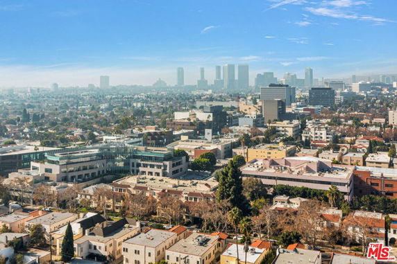 Aerial view of an urban area with a mix of residential and commercial buildings, against a backdrop of a city skyline.