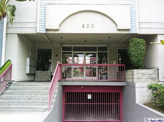 Front view of an apartment building entrance with stairs and a gated entrance below.