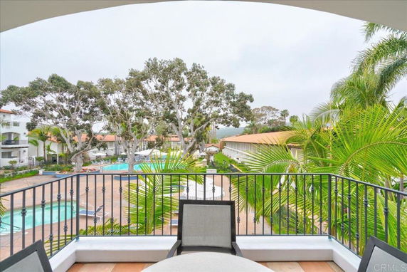 View from a balcony overlooking a courtyard with a swimming pool, surrounded by trees and buildings.