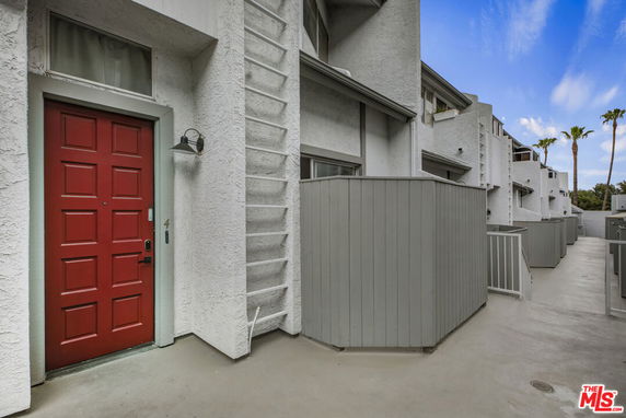 Front view of a multi-story building with a red door and gray exterior.