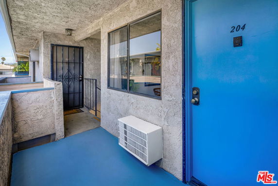 Exterior view of an apartment entrance with blue door and window.