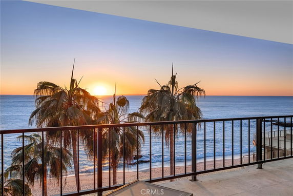 Panoramic view of a beach and ocean from a balcony during sunset.