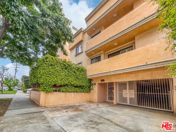 Front view of a multi-story residential building with balconies and gated entrance.