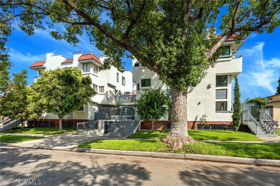 Front view of a multi-story residential building with balconies and stairs.