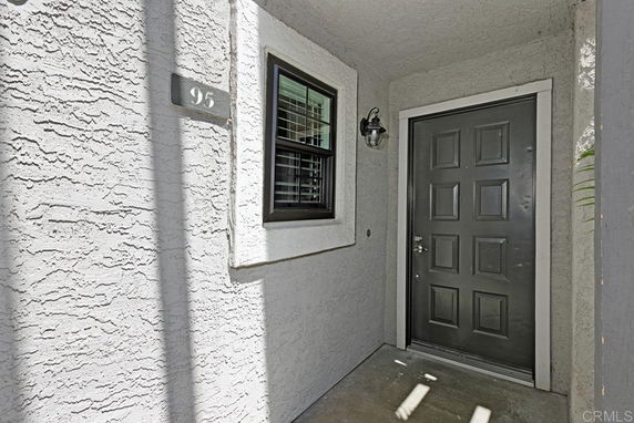 Front view of an entryway with a dark door and single window on a textured wall.