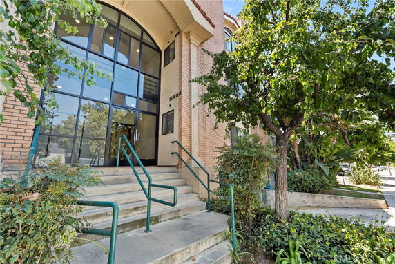 Front view of a building with large windows and stairs leading to the entrance.