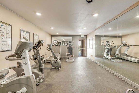 Indoor gym area with exercise equipment and mirrored wall.