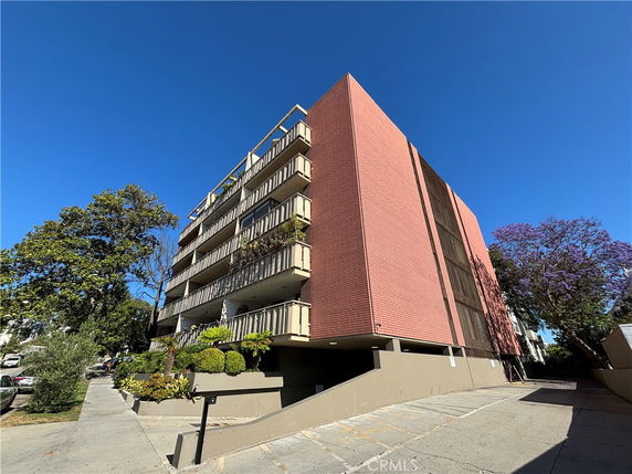 Front view of a multi-story building with balconies and a brick facade.